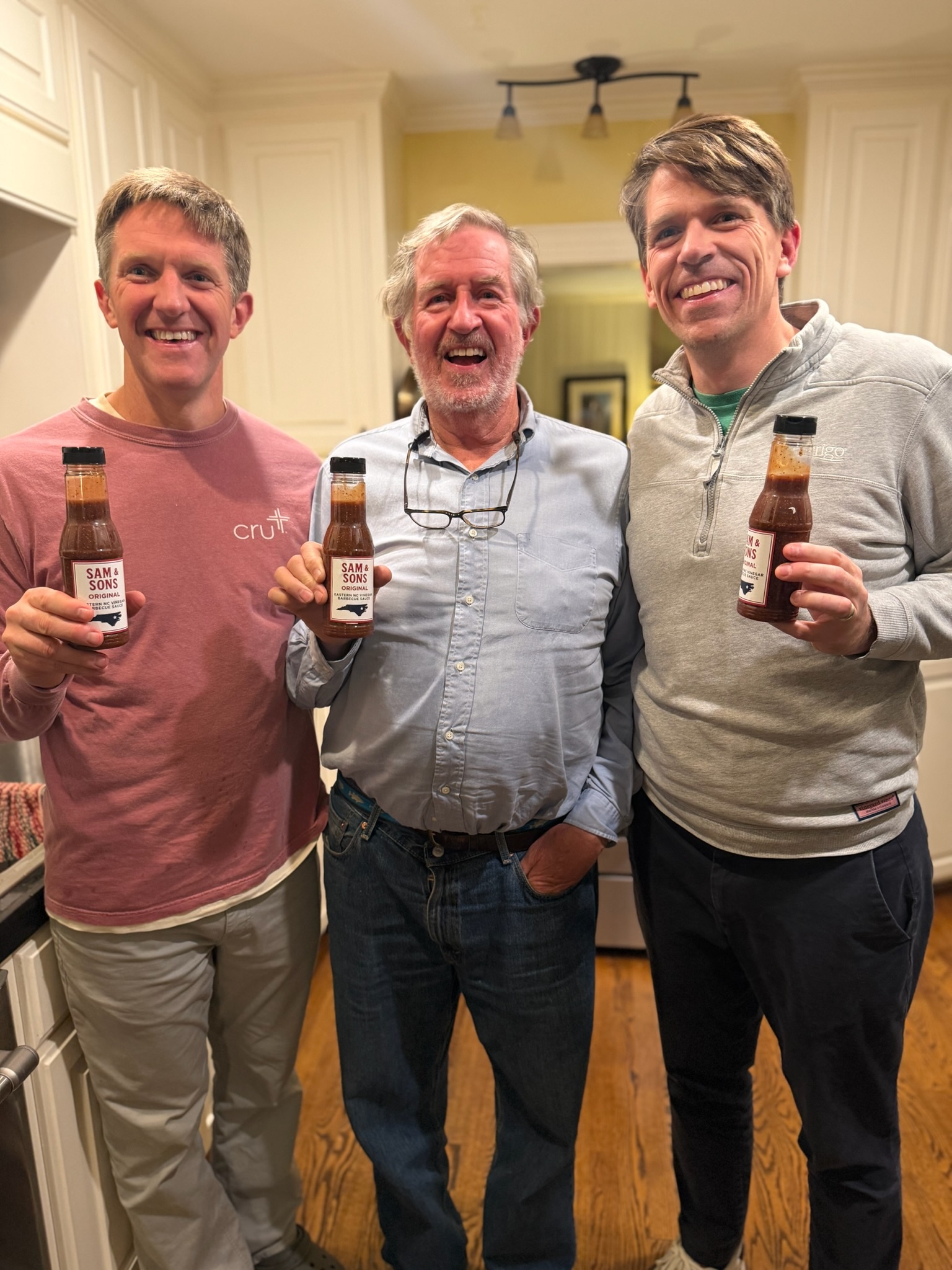 Sam and his two sons holding bottles of their family barbecue sauce